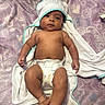 baby, bed, blanket, child, cloth, cute, diaper, hand, holding_hands, hooded_towel, indoors, infant, looking_at_camera, lying_down, patterned, person, purple, skin, soft_texture, towel