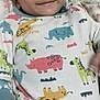 baby, child, smiling, onesie, animal_print, hand, face, lying_down, blanket, floral_pattern, cute, infant, happy, portrait, indoor, person, clothing, young_child, head, skin