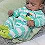 baby, infant, onesie, striped_clothing, baby_seat, cushion, hand, indoor, curious, face, head, sitting, footwear, green, white, soft_fabric, comfort, person, closeup, child