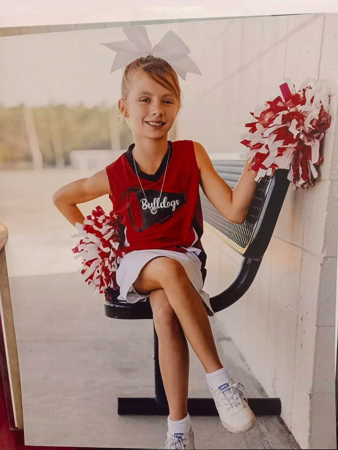 Kinslee is registered to the contest to win money with this photo: beauty, calf, carmine, cheerleading_uniform, competition_event, electric_blue, event, fashion_accessory, fashion_design, happy, human_leg, joy, knee, leg, person, shorts, sitting, smile, sneakers, sportswear