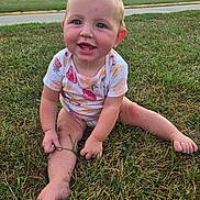 Lyra is registered to the contest to win money with this photo: baby, child, infant, smiling, sitting, grass, outdoor, park, portrait, face, blue_eyes, blond_hair, floral_clothing, fruit_pattern, onesie, barefoot, painted_toenails, road, trees, cars