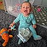 Lyra joined the competition — help win amazing prizes! baby, child, smiling, sitting, portrait, indoor, playroom, playpen, rug, stuffed_toy, orange_toy, rattle, baby_clothes, onesie, pacifier_case, toys, infant, happy, face, family_home
