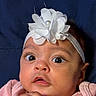 baby, infant, face, headband, flower, pink_clothing, hands, wide_eyes, curious, portrait, closeup, soft_skin, cute, child, young, adorable, indoors, expression, headwear, person