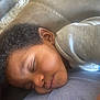 Mecca is registered to the contest to win money with this photo: child, toddler, sleeping, curly_hair, face, head, skin, clothing, shirt, resting, peaceful, indoors, portrait, closeup, soft_light, person, cute, relaxed, nap, young