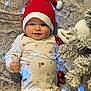 Killian participe au concours pour gagner de l'argent avec cette photo : baby, blanket, celebration, child, christmas_tree, cozy, cute, decorations, fairy_lights, festive, happy, holiday, indoor, infant, lying_down, onesie, ornament, santa_hat, seasonal, smiling