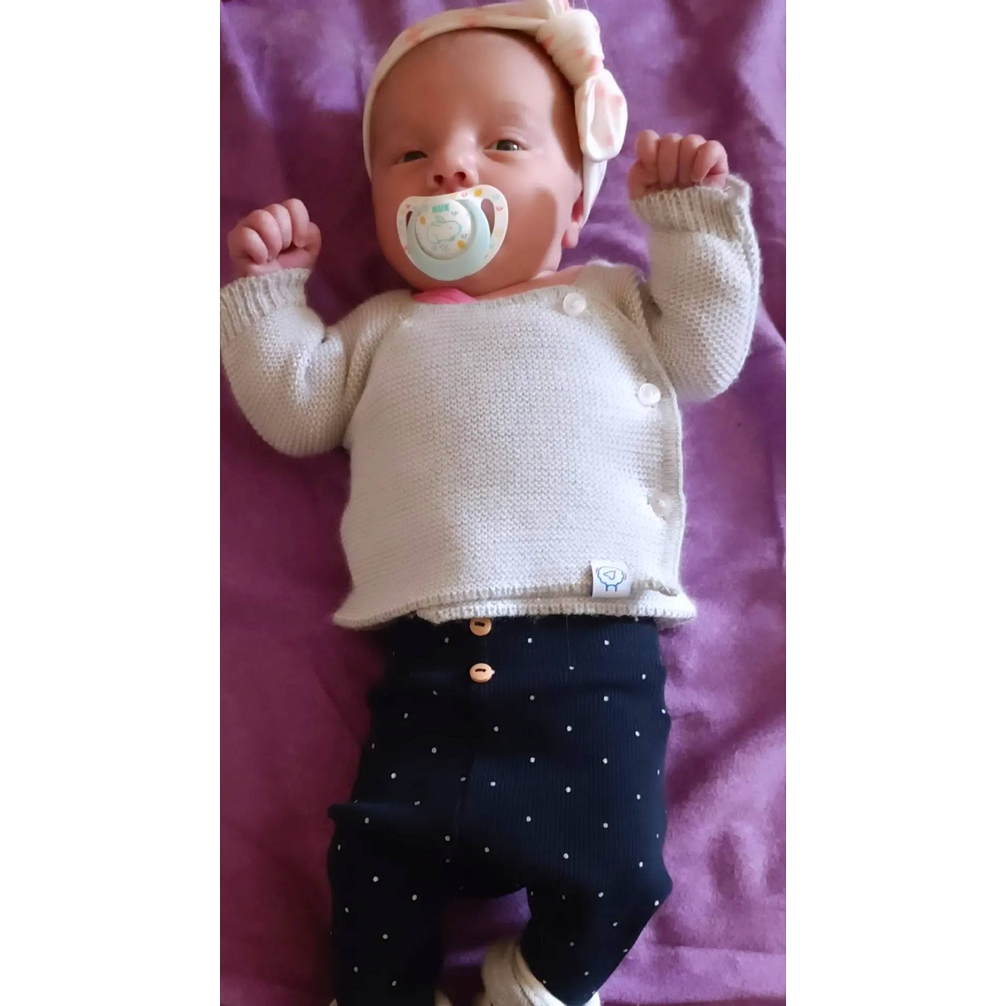 Louna participe au concours pour gagner de l'argent avec cette photo : arm, baby, baby_toddler_clothing, child, doll, finger, gesture, headgear, human_body, leg, neck, outerwear, person, pink, purple, sleeve, t_shirt, thigh, toy, violet