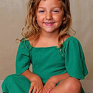 Lahna participe au concours pour gagner de l'argent avec cette photo : child, girl, smile, green_dress, curly_hair, sitting, cross_legged, sandals, nail_polish, pink, blue, portrait, studio, happy, cute, fashion, young, skin, face, hands