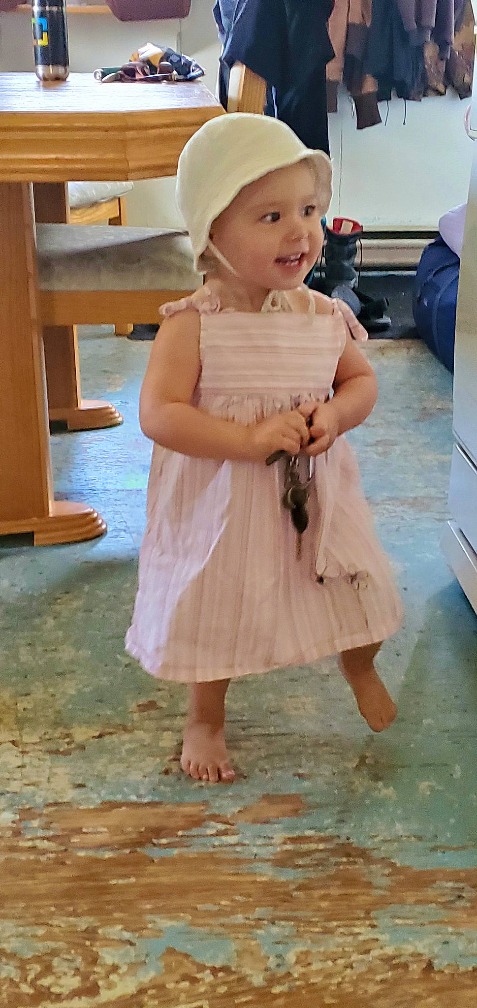 Rebecca a rejoint le concours — aidez-le/la à gagner de superbes lots ! baby_toddler_clothing, barefoot, cap, child, day_dress, dress, flooring, foot, fun, happy, hat, headwear, human_leg, person, pink, skin, sleeve, smile, standing, toddler