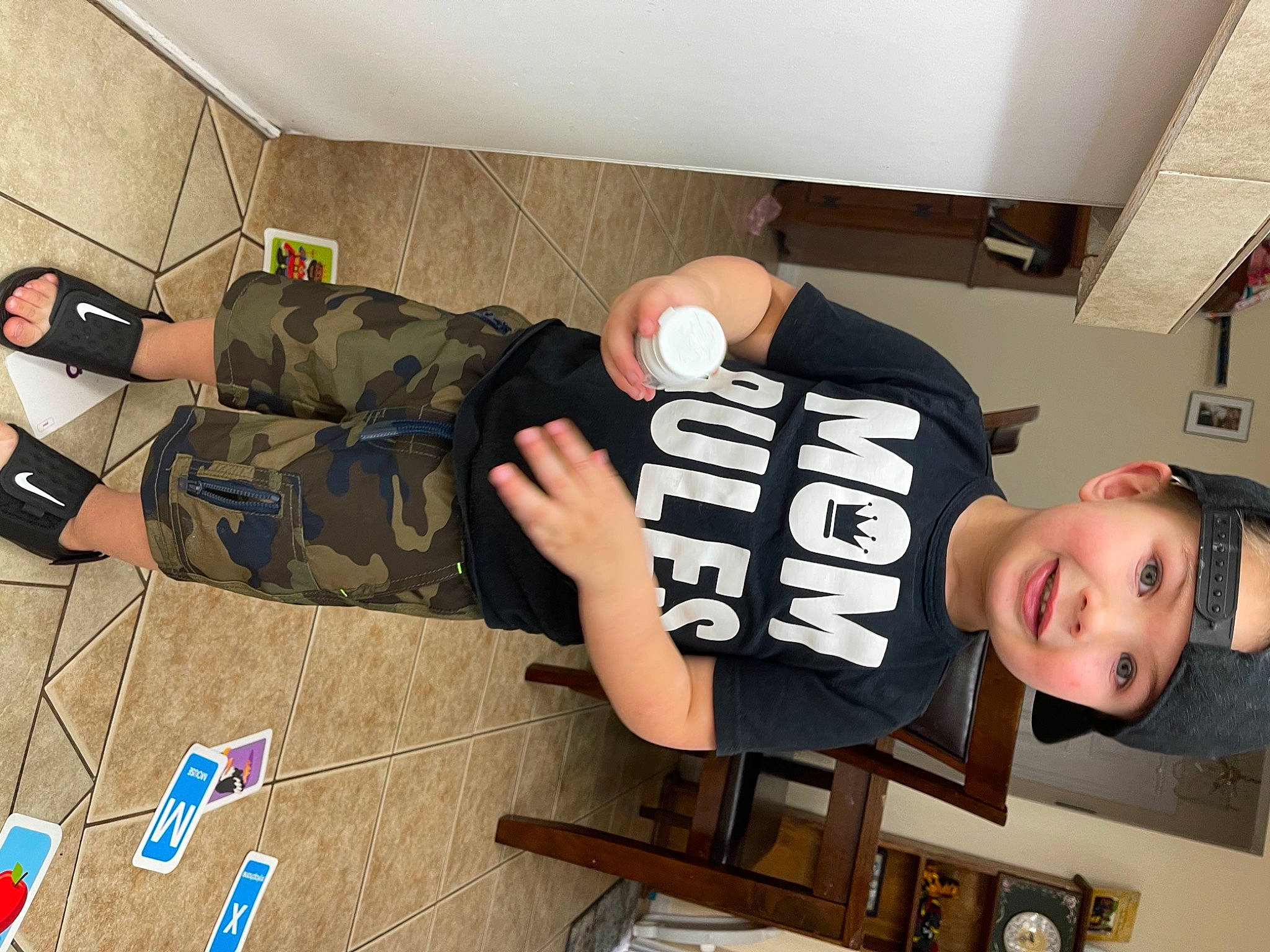 Trey is registered to the contest to win money with this photo: bag, boot, elbow, eyewear, flooring, fun, happy, headwear, human_leg, joint, joy, knee, leg, military_camouflage, person, room, shoe, shorts, sleeve, smile
