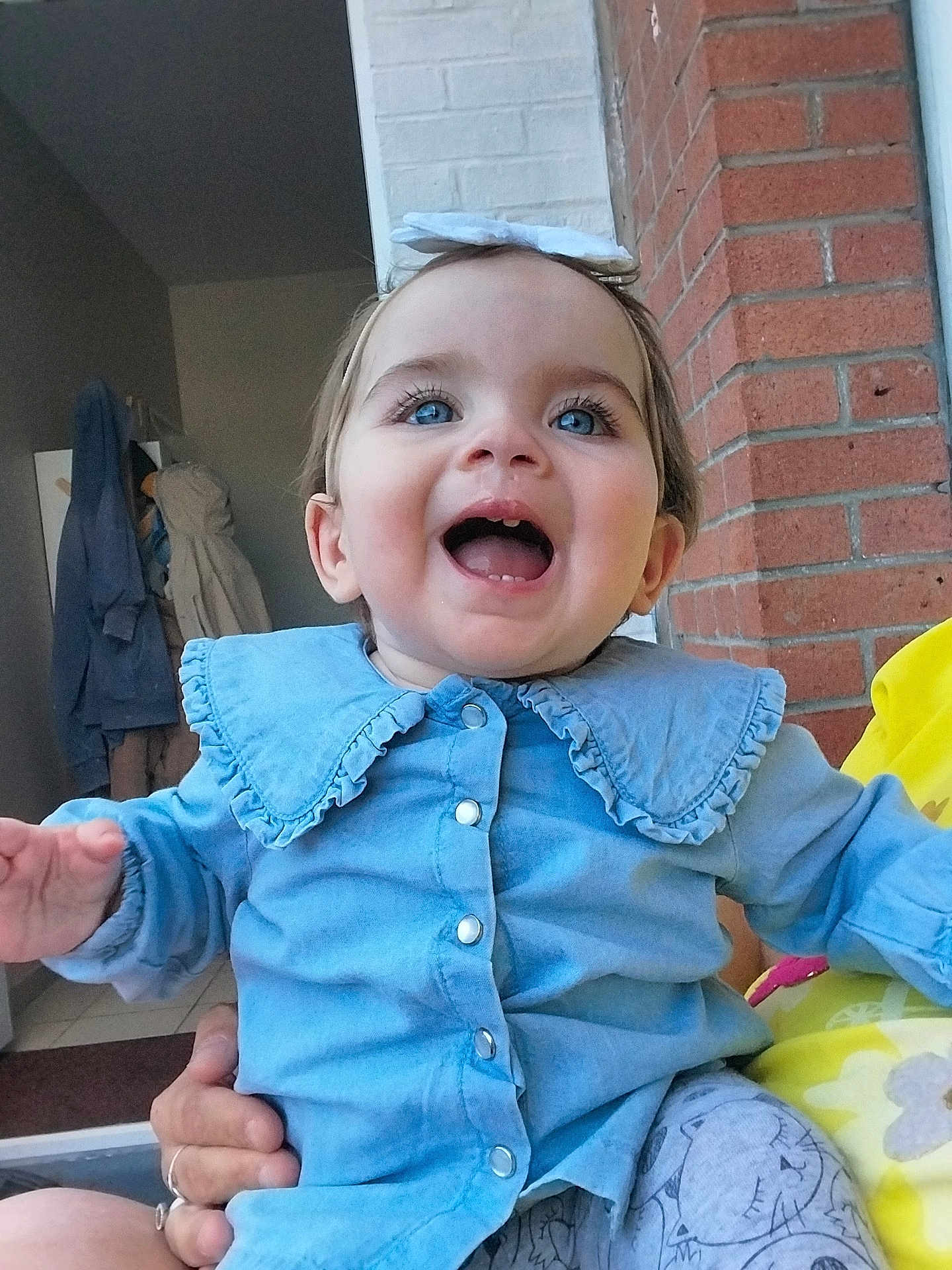 Louméa participe au concours pour gagner de l'argent avec cette photo : toddler, child, blue_eyes, smiling, happy, indoor, clothing, headband, bow, blue_shirt, baby, person, face, hand, brick_wall, coat, doorway, holding, candid, portrait