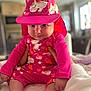 baby, child, pink_clothing, unicorn_pattern, hat, indoors, cute, infant, person, sitting, smiling, hand, soft_light, blanket, bedroom, cute_outfit, closeup, face, headwear, playful
