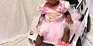 Ava-Rae is registered to the contest to win money with this photo: balloon, child, clothing, face, female, footwear, furniture, girl, head, machine, person, photography, portrait, shoe, sitting, sleeve, toy, transportation, vehicle, wheel