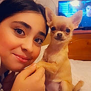 Savanah participe au concours pour gagner de l'argent avec cette photo : person, dog, chihuahua, pet, selfie, bedroom, smile, eyes, ears, bed, blanket, remote_control, television, furniture, human_face, animal_face, paw, indoor, cute, holding