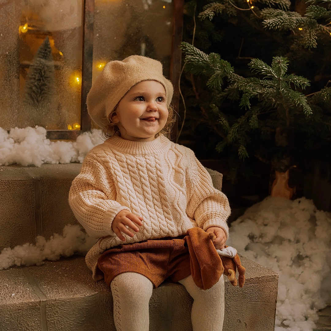 Ambre participe au concours pour gagner de l'argent avec cette photo : beret, boots, child, cozy, cute, fairy_lights, faux_snow, festive, frosted_window, holiday, indoor, knitted_sweater, pine_tree, playful, seasonal, smile, stone_steps, toddler, warm_lighting, winter_clothing
