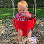toddler, baby, swing, playground, outdoor, child, greenery, wood_chips, sunlight, red_swing, sandals, pink_shirt, trees, summer, park, play, face, legs, footwear, nature