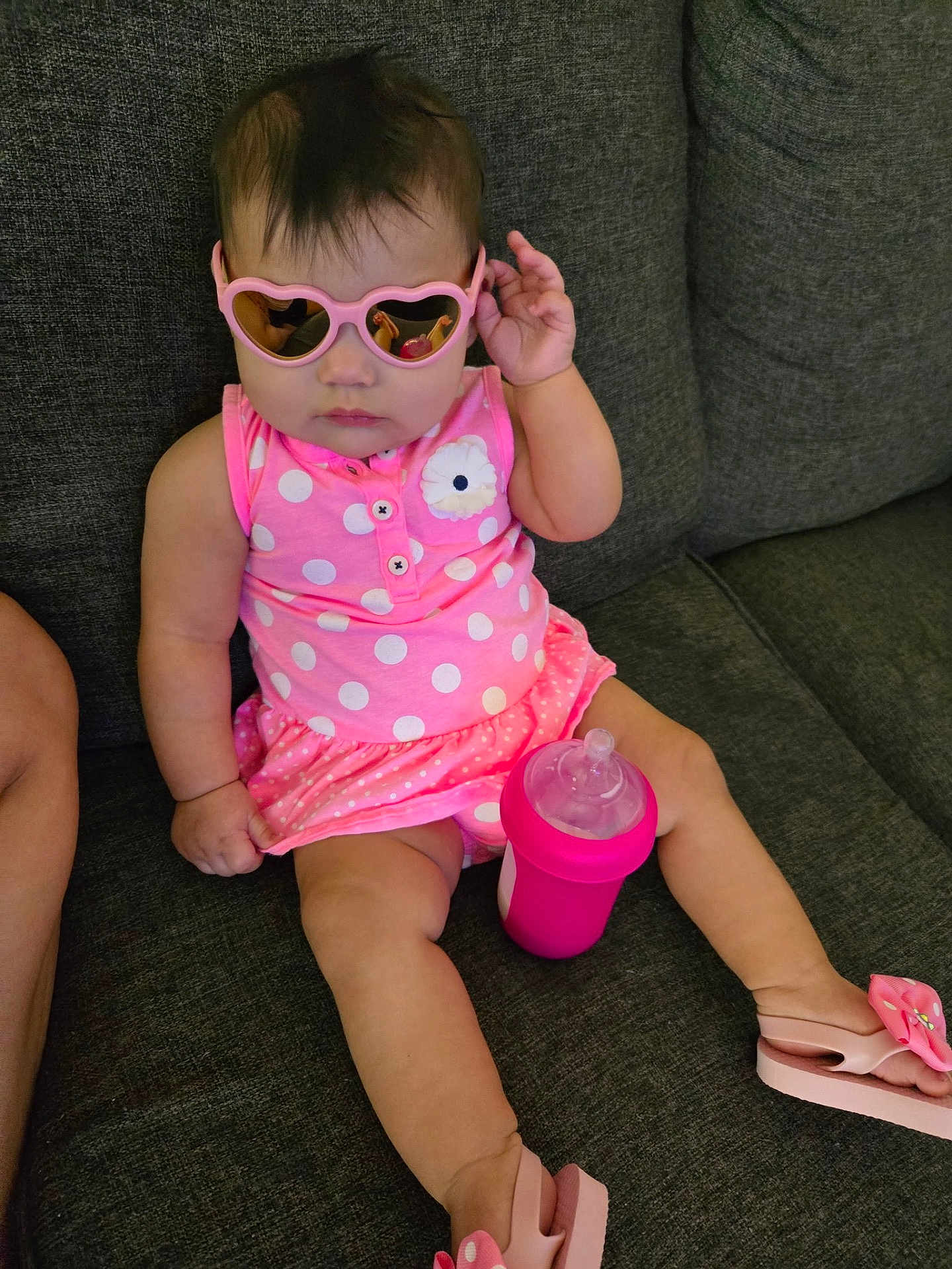 Gracie joined the competition — help win amazing prizes! baby, child, sunglasses, pink, polka_dot, dress, sippy_cup, couch, footwear, flip_flops, indoor, cute, portrait, sitting, person, infant, fashion, accessory, relaxing, home