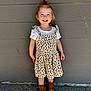Ava is registered to the contest to win money with this photo: brown_boots, casual, child, concrete_floor, cute, daylight, dress, fashion, gray_wall, hair_ponytail, happy, leopard_print, outdoor, person, portrait, small_toy, smiling, standing, toddler, white_shirt