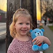 Ava joined the competition — help win amazing prizes! child, smiling, teddy_bear, plush_toy, outdoor, sunset, telephone_pole, wooden_pole, sidewalk, street, patterned_shirt, pink_shirt, portrait, happy, blond_hair, hand, bokeh, urban, person, photography