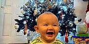 Finley joined the competition — help win amazing prizes! baby, celebration, child, christmas_lights, christmas_tree, decorations, face, festive, floor, gift_boxes, happy, holiday, indoor, ornaments, pajamas, person, sitting, smiling, striped_clothing, toy
