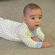 Steven is registered to the contest to win money with this photo: baby, infant, child, crawling, lying_down, carpet, indoor, portrait, face, eyes, curious, looking_at_camera, pajamas, patterned_clothing, blue, white, hands, floor, home, photograph