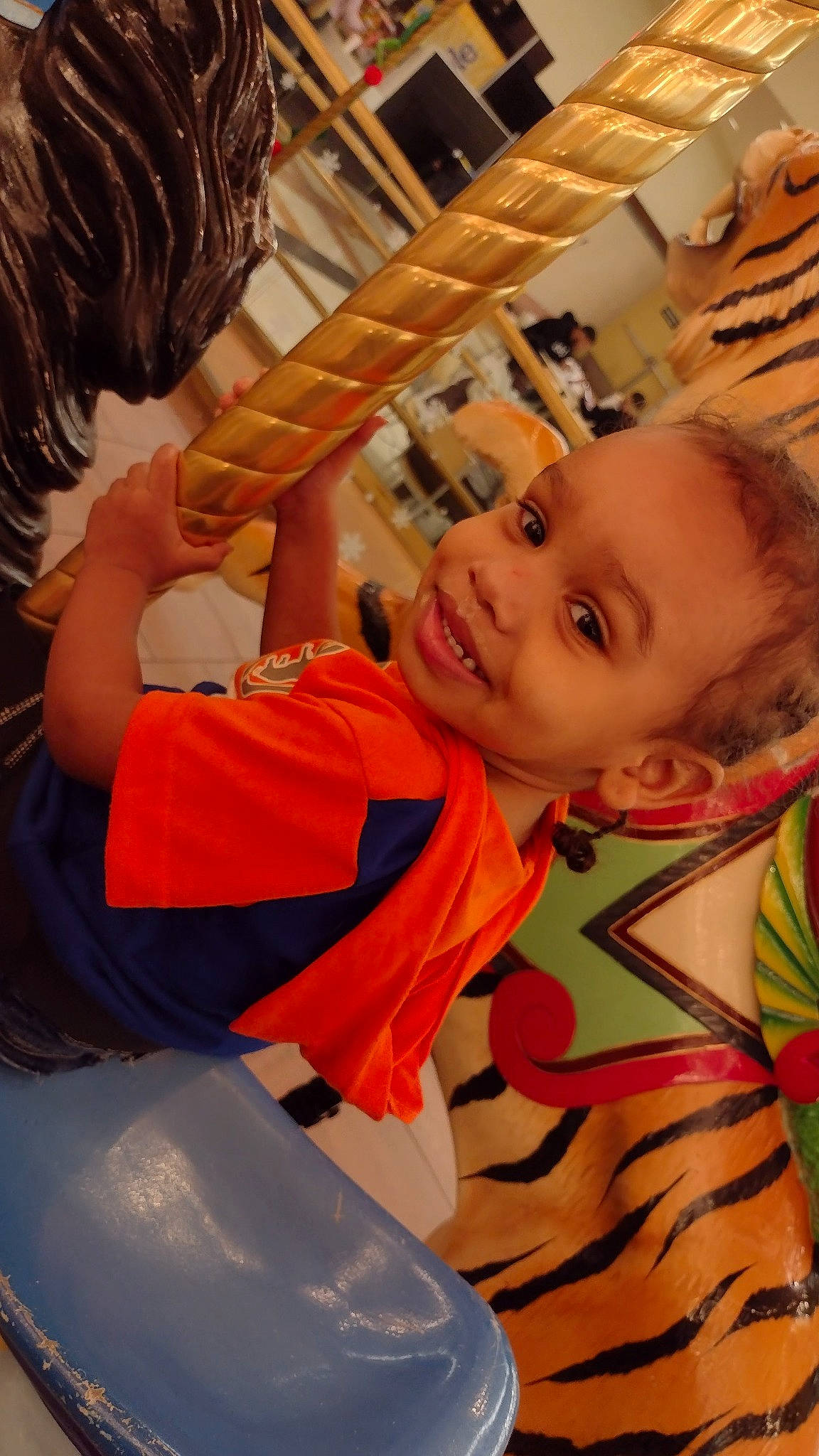 Prince is registered to the contest to win money with this photo: blond, chair, child, comfort, facial_expression, finger, fun, hairstyle, happy, joy, leisure, mouth, muscle, orange, organ, person, room, sitting, smile, t_shirt