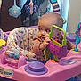 Elena is registered to the contest to win money with this photo: baby, child, activity_center, toy, purple, pink, green, colorful, indoor, infant, play, seat, face, curious, hand, plastic, patterned_clothing, developmental_toy, early_childhood, expression