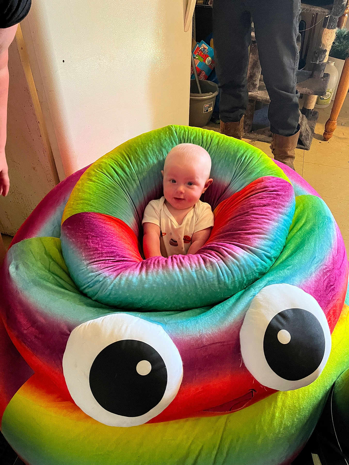 Malachi is registered to the contest to win money with this photo: baby, infant, bean_bag, colorful, rainbow, poop_emoji, indoor, person, smiling, plush, furniture, child, cute, seat, toy, soft, candid, happy, home, googly_eyes