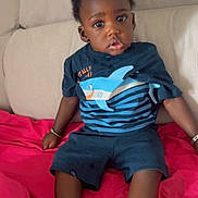 Iyad a rejoint le concours — aidez-le/la à gagner de superbes lots ! child, toddler, baby, sitting, sofa, blanket, clothing, shirt, shorts, socks, indoor, person, face, expression, curly_hair, bracelet, casual, home, comfort, cute
