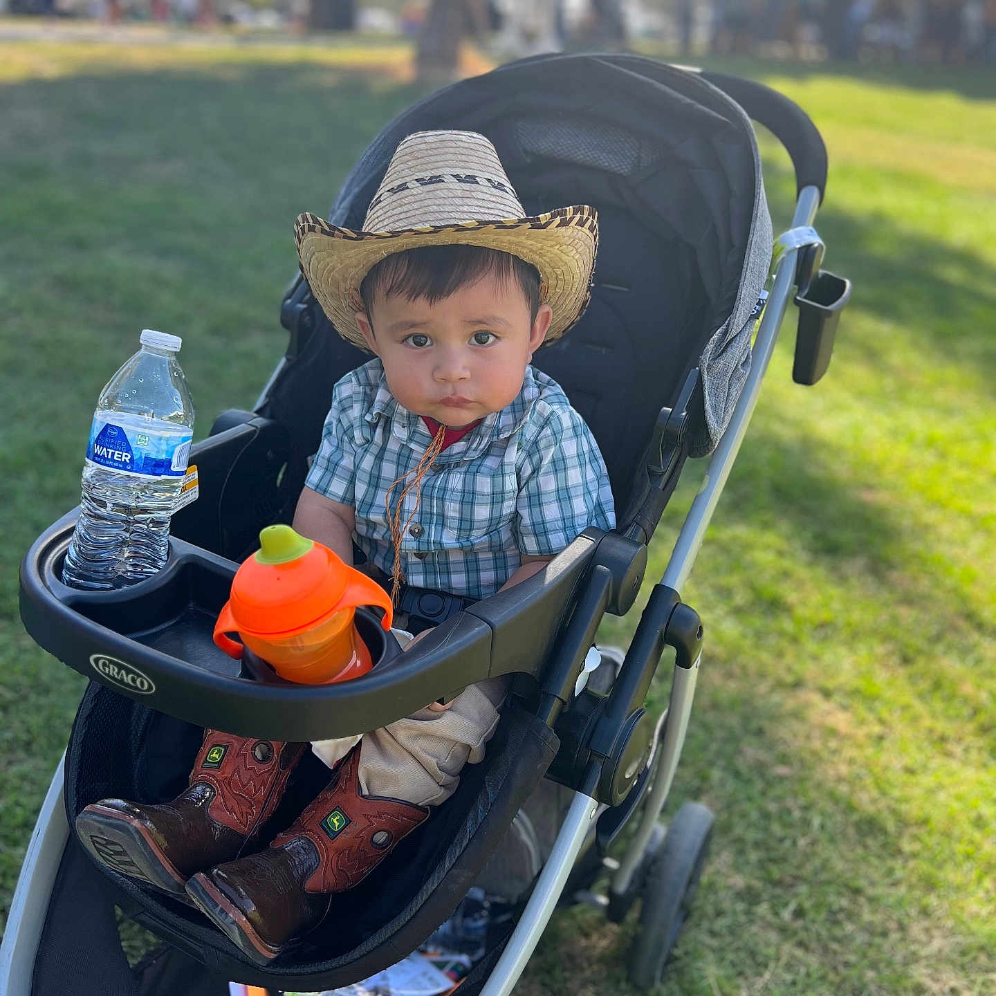 Nathaniel is registered to the contest to win money with this photo: baby, bottle, clothing, face, footwear, grass, hat, head, machine, nature, outdoors, park, person, photography, plant, portrait, shoe, sunhat, waterbottle, wheel