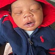 Adonis is registered to the contest to win money with this photo: baby, child, sleeping, hoodie, red_hood, navy_blue_clothing, face, mouth_open, cozy, cute, infant, portrait, young_child, indoors, person, apparel, zipper, headwear, peaceful, closeup