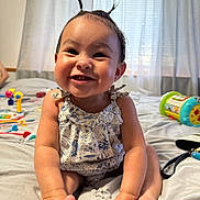 Maliyah joined the competition — help win amazing prizes! baby, smiling, child, indoor, bed, toys, hair, cute, happy, person, clothing, face, feet, furniture, room, curtains, playful, infant, skin, expression