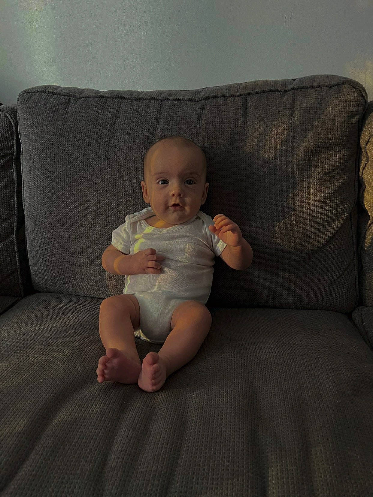 Rafaël participe au concours pour gagner de l'argent avec cette photo : baby, baby_toddler_clothing, chair, cheek, comfort, couch, finger, flooring, foot, head, human_leg, knee, lap, leg, living_room, person, sitting, sock, thigh, toddler