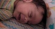 Cayden is registered to the contest to win money with this photo: baby, blanket, child, closeup, colorful, cozy, cute, face, head, indoors, infant, newborn, patterned_blanket, peaceful, person, resting, sleeping, soft, striped_clothing, young