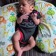 Cayden joined the competition — help win amazing prizes! animal_print, baby, baby_boy, black_clothing, curious_expression, cute, giraffe, hippopotamus, indoor, infant, leather_chair, lion, newborn, onesie, owl, pillow, portrait, red_clothing, seated, small_hands