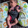 baby, infant, onesie, black_clothing, red_clothing, animal_print, pillow, giraffe, lion, owl, hippopotamus, leather_chair, baby_boy, cute, portrait, newborn, indoor, seated, small_hands, curious_expression