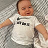 baby, smiling, tshirt, nike, just_do_it, shorts, blanket, patterned_blanket, infant, happy, lying_down, arms_outstretched, cute, child, face, clothing, indoor, person, young_child, text_on_clothing