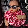 David is registered to the contest to win money with this photo: baby, infant, sunglasses, red_striped_clothing, car_seat, child, seatbelt, portrait, cute, fashion, accessory, hand, face, head, casual, young_child, indoors, relaxing, person, babywearing