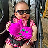 baby, sunglasses, plush_toy, stroller, child, smiling, red_striped_clothing, seat_belt, indoor, wooden_floor, happy, person, toy, fun, cute, infant, casual, comfort, playful, relaxed