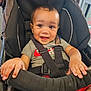 baby, black, car_seat, child, clothing, cute, eyes, fabric, face, gray_shirt, hair, happy, indoors, red_shorts, safety_harness, seat, short_sleeve, small_hands, smiling, toddler