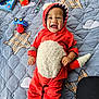 Mateo is registered to the contest to win money with this photo: baby, blanket, child, cloud_pattern, colorful, cute, face, footwear, hands, happy, headwear, indoors, infant, playtime, plush, quilted, red_onesie, smiling, star_pattern, toy