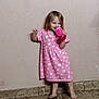 child, girl, pink_dress, barefoot, holding_cup, smiling, standing, indoor, wall, floor_tiles, long_hair, playful, happy, casual, young_child, person, portrait, cute, bare_footed, drinking