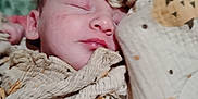 Makenzie is registered to the contest to win money with this photo: baby, sleeping, blanket, cozy, patterned_clothing, infant, face, peaceful, soft_lighting, closeup, child, rest, cute, wrapped, indoors, portrait, sleep, young_child, skin, head