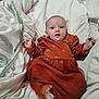 baby, infant, dress, orange_clothing, blanket, white_blanket, soft_texture, foot, hand, face, curious_expression, lying_down, indoors, cute, child, newborn, cozy, portrait, small_toes, comfortable
