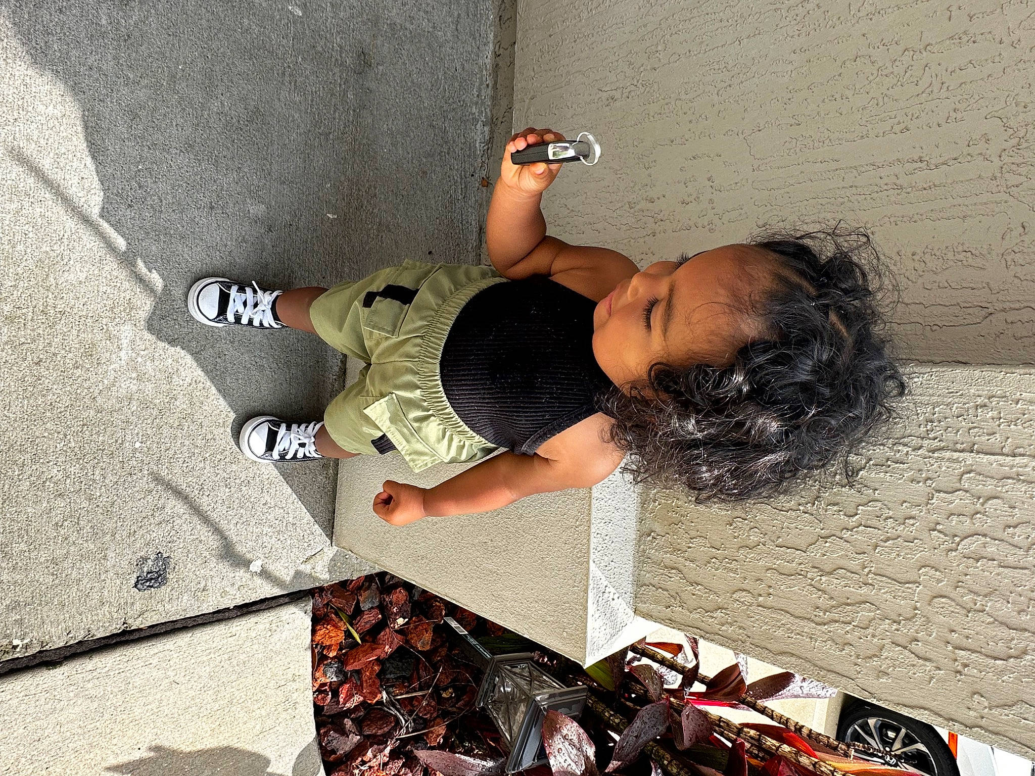 Kaia is registered to the contest to win money with this photo: asphalt, child, concrete, elbow, eyewear, flooring, foot, human_body, human_leg, leisure, person, recreation, road_surface, sandal, shadow, sidewalk, sitting, thigh, toddler, visual_arts