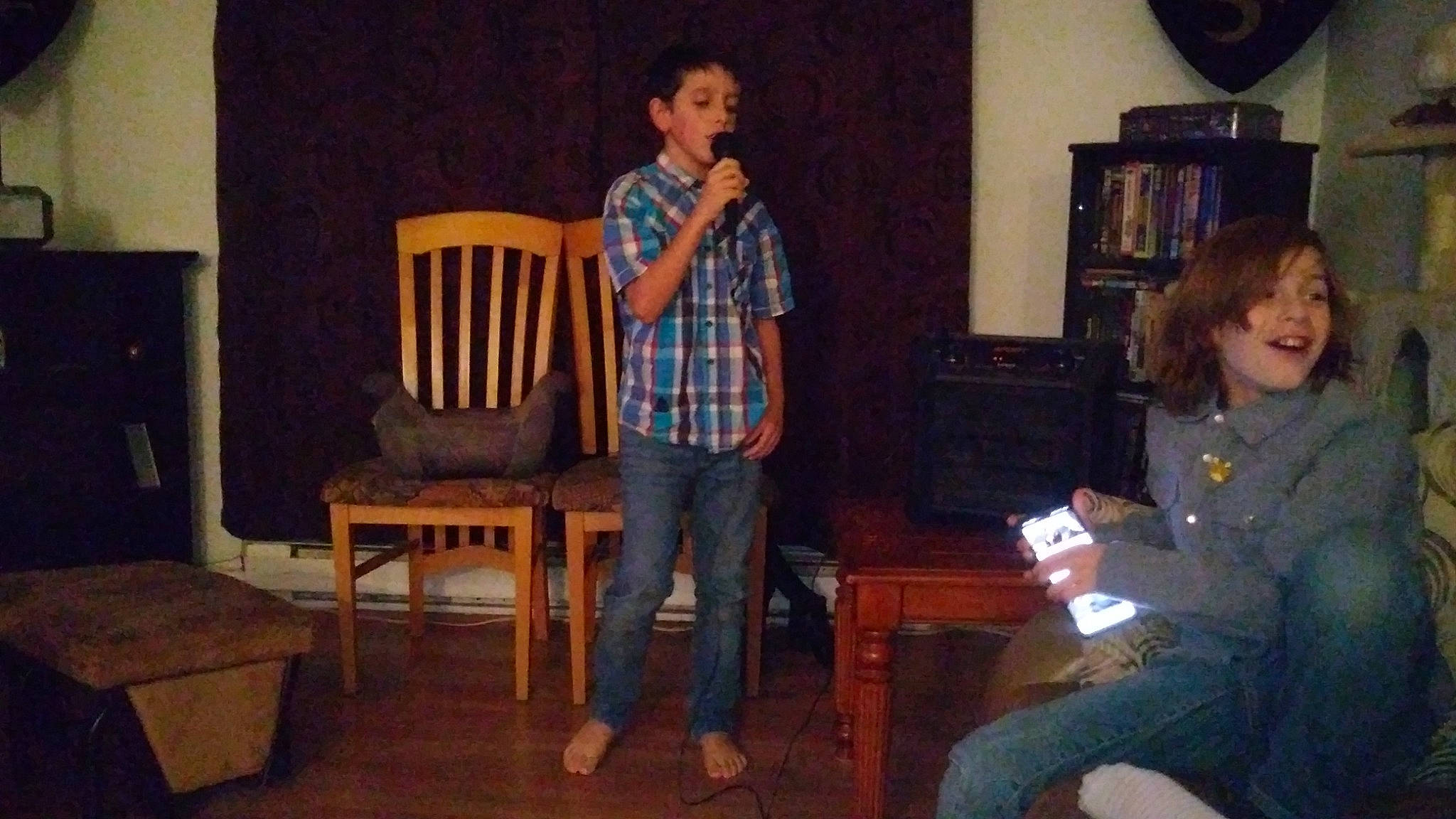 Loik is registered to the contest to win money with this photo: bookcase, chair, clothing, coffee_table, conversation, entertainment, event, fun, furniture, hardwood, jeans, leg, leisure, lighting, living_room, person, picture_frame, shelf, standing, t_shirt