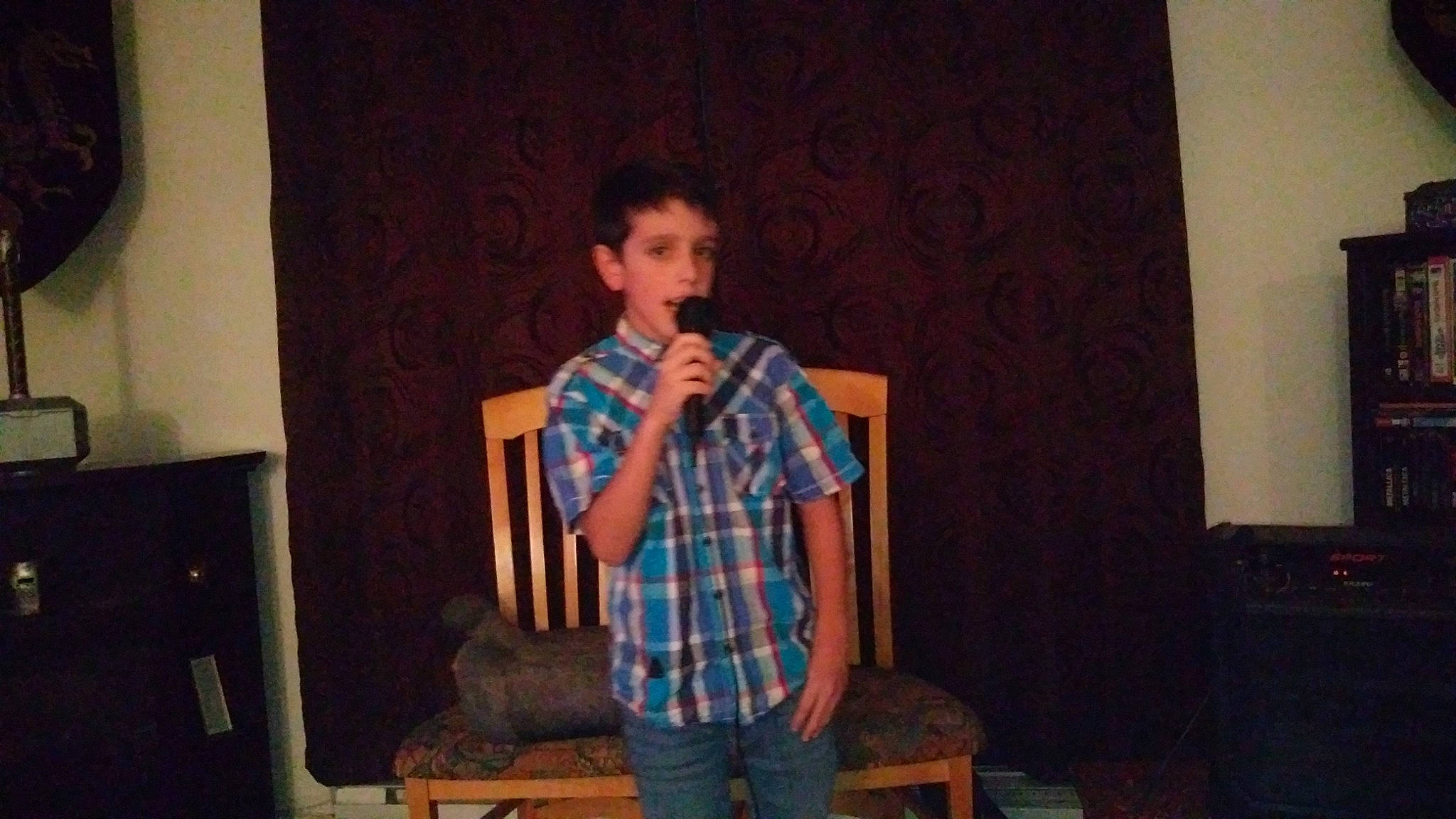 Loik is registered to the contest to win money with this photo: audio_equipment, chair, curtain, entertainment, event, fun, microphone, music, musician, pattern, performing_arts, person, plaid, presentation, public_speaking, room, speech, stage_equipment, stool, t_shirt