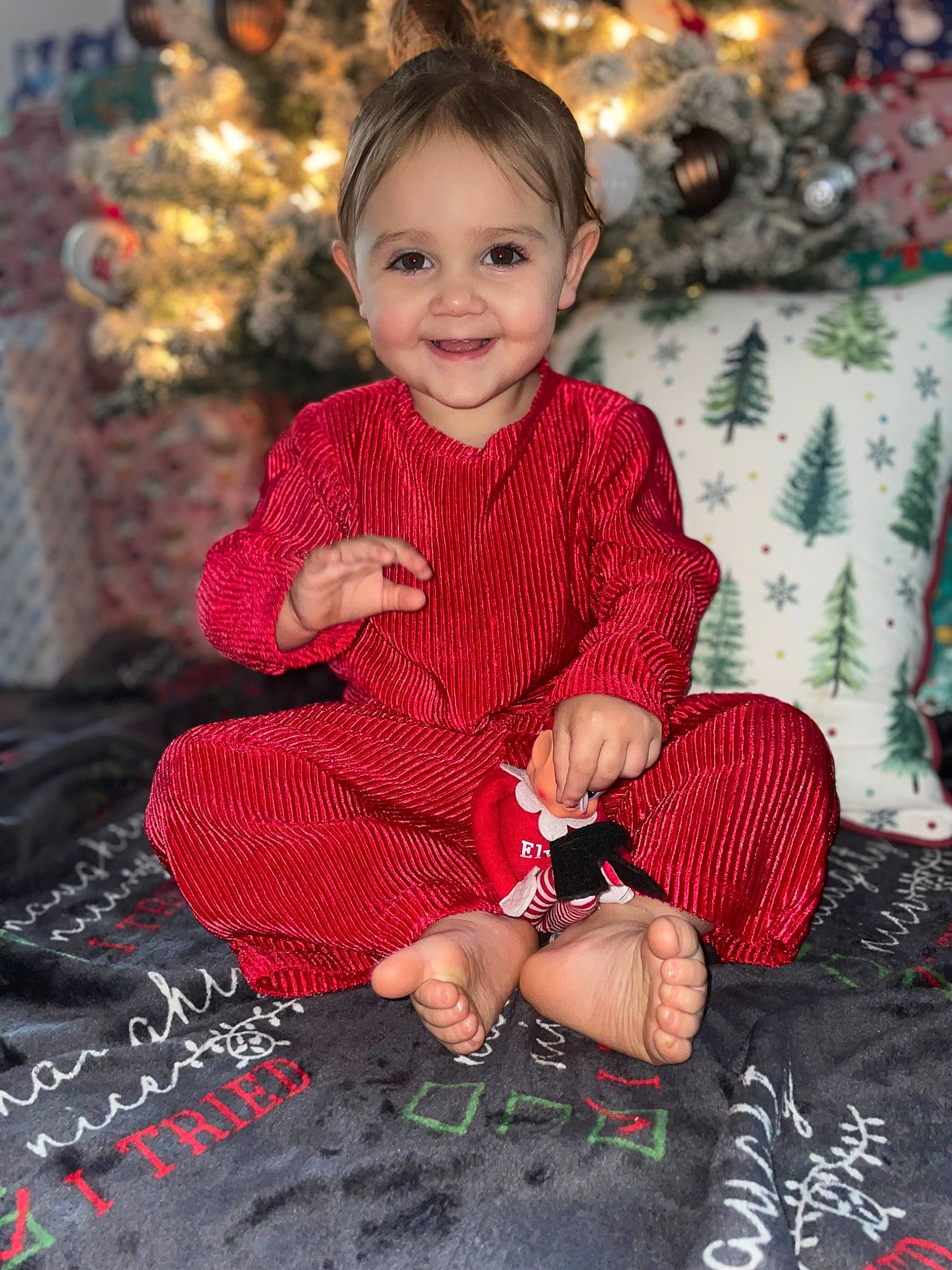 Annalise joined the competition — help win amazing prizes! baby_toddler_clothing, child, christmas_decoration, christmas_ornament, christmas_tree, dress, event, face, facial_expression, happy, head, holiday, joy, ornament, pattern, person, sitting, skin, sleeve, smile