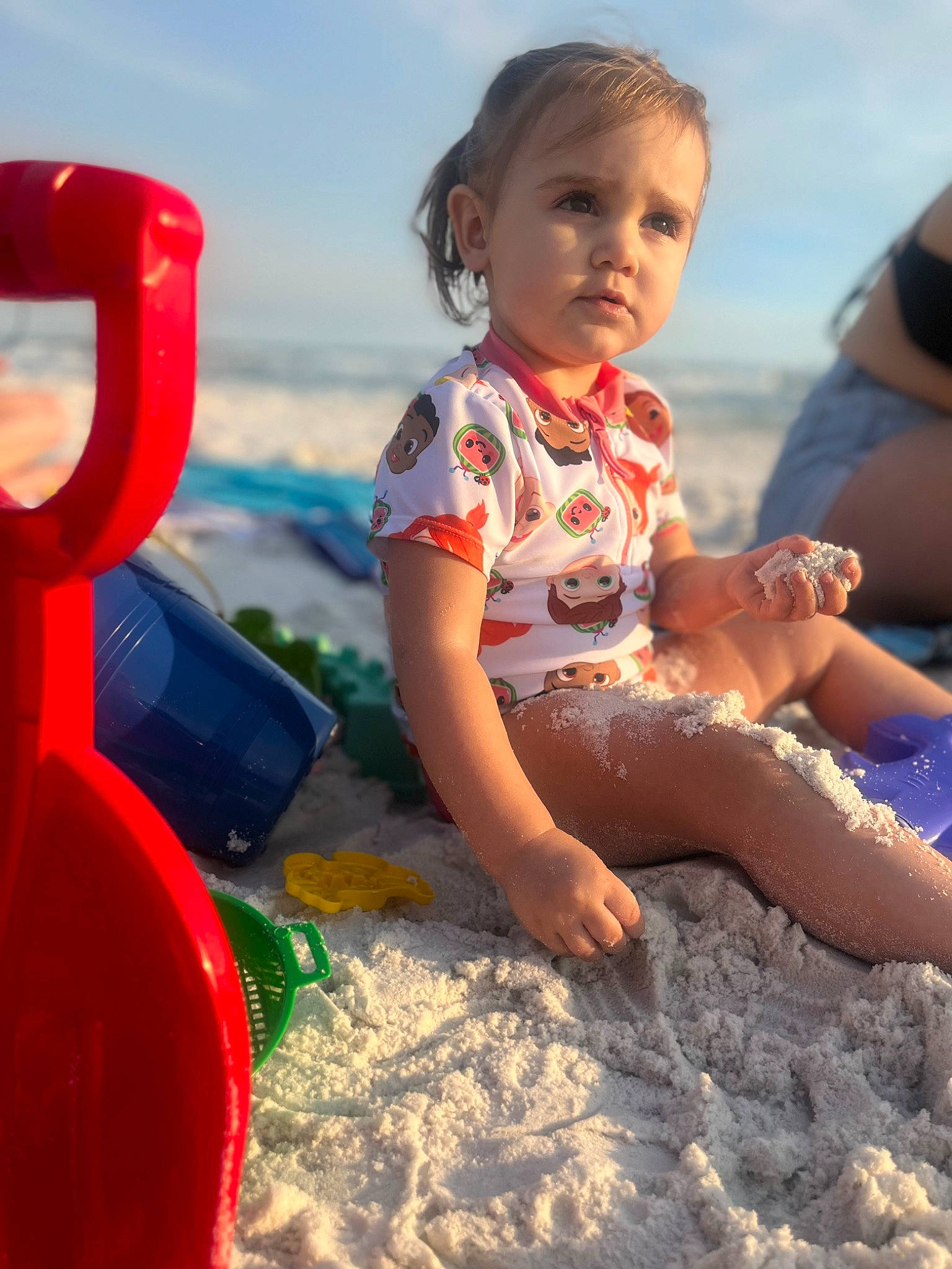 Annalise joined the competition — help win amazing prizes! baby_toddler_clothing, barefoot, beach, body_of_water, child, cloud, fun, happy, leisure, people_in_nature, people_on_beach, person, play, recreation, sand, sitting, sky, t_shirt, thigh, toddler