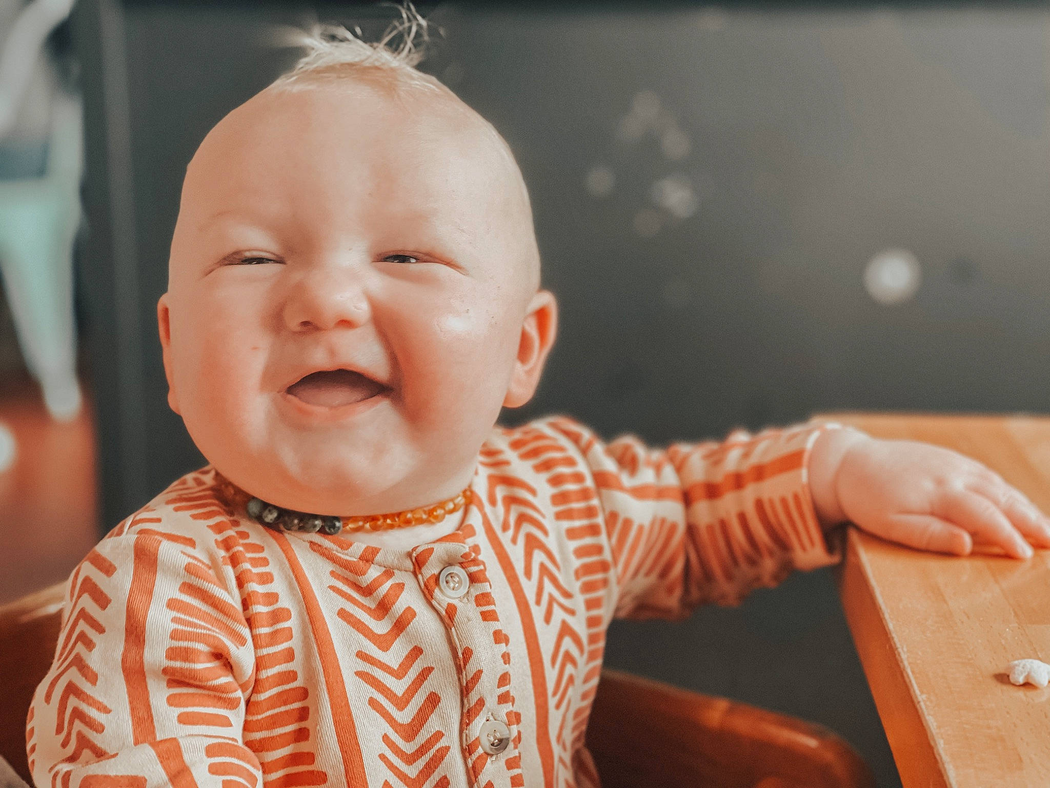 Hollis is registered to the contest to win money with this photo: baby, baby_toddler_clothing, cheek, child, clothing, ear, face, facial_expression, fun, happy, head, iris, nose, orange, person, sitting, skin, sleeve, smile, table