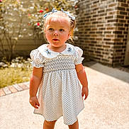 Willow joined the competition — help win amazing prizes! backyard, bows, brick_wall, child, concrete, curious, cute, dress, flowers, girl, greenery, hair_accessory, outdoor, polka_dot, portrait, shoes, standing, summer, sunlight, toddler